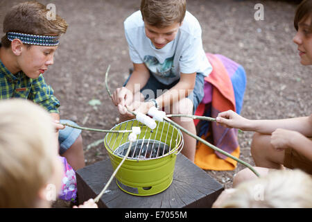 Gruppo di ragazzi tostare marshmallows su barbecue della benna Foto Stock