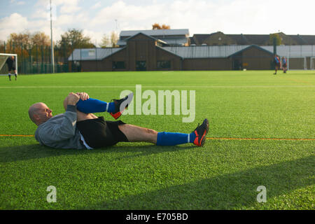 Giocatore di football stretching prima del gioco Foto Stock