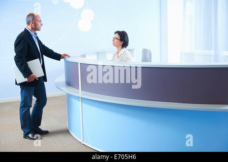 Adulto Uomo parlando a receptionist Foto Stock