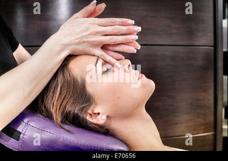 Massaggiatore femminile giovane massaggio volto di donna nel salone di bellezza Foto Stock