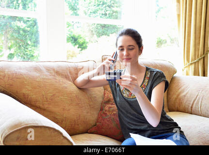 Giovane donna seduta sul divano home shopping su linea telefonica fissa Foto Stock