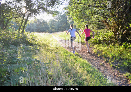 Due giovani runner donna corre su pista forestale in mattinata Foto Stock