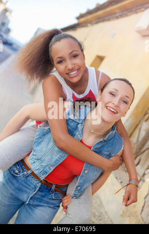 Ragazza adolescente dando amico piggyback ride Foto Stock