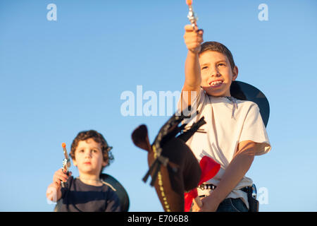 Due fratelli vestito da cowboy di puntamento pistole giocattolo Foto Stock