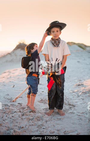 Due fratelli vestito da cowboy's raggiungendo per hat Foto Stock