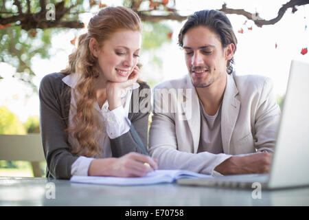 Imprenditore e collega femmina rendendo note durante una riunione informale in giardino Foto Stock