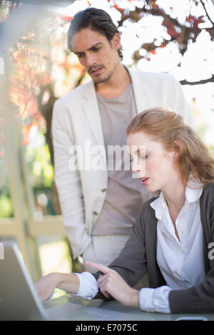 Imprenditore e collega di sesso femminile guardando portatile nel corso di una riunione informale in giardino Foto Stock