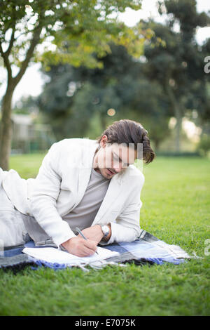 Imprenditore reclinata su Coperta picnic scrivere note in posizione di parcheggio Foto Stock