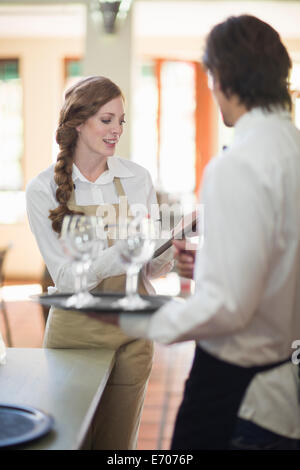 Cameriere e cameriera portava vassoi di bicchieri di vino nel ristorante Foto Stock