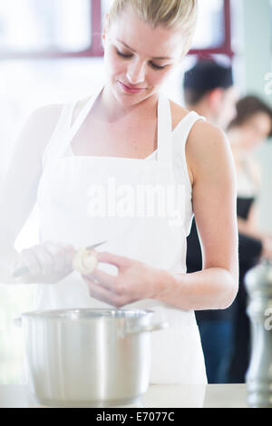 Lo chef femmina sbucciare le patate in una cucina commerciale Foto Stock