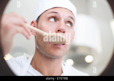 Maschio degustazione chef cibo dalla pentola in cucina commerciale Foto Stock