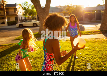 Le tre ragazze giocare con acqua palloncini in giardino Foto Stock