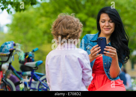 Giovane madre figlio di fotografia sullo smartphone in posizione di parcheggio Foto Stock