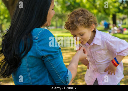 Giovane madre e figlio odore di fiore nel parco Foto Stock