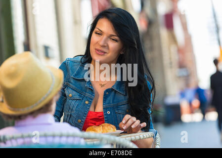 Giovane madre e figlio avente torta al cafè sul marciapiede Foto Stock