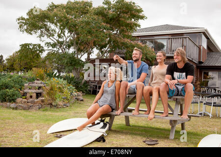 Quattro amici surfista seduta sul banco per picnic Foto Stock