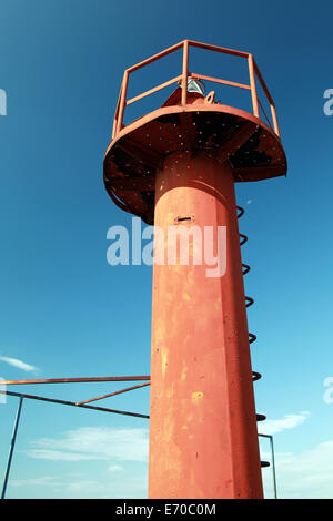 Piccolo faro rosso sopra Palo profondo cielo blu Foto Stock