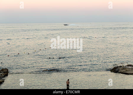 Un uomo si fermò in un mare piscina sulla spiaggia di Sliema , Malta , si affaccia al mare a sunrise Foto Stock