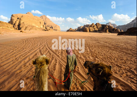 La Giordania. Il Wadi Rum è anche conosciuta come la Valle della Luna. Dromedario corsa attraverso il deserto. Foto Stock