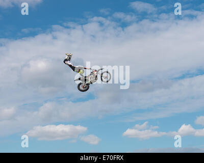 FMX moto rider completando le acrobazie sullo sfondo di un cielo blu con nuvole Foto Stock