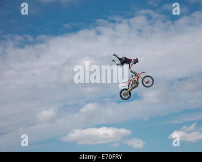 FMX moto rider completando le acrobazie sullo sfondo di un cielo blu con nuvole Foto Stock