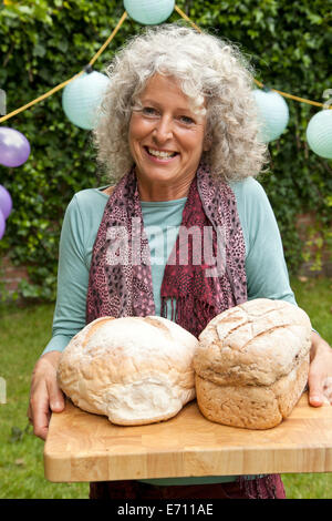 Ritratto di donna matura con focacce di pane al party in giardino Foto Stock