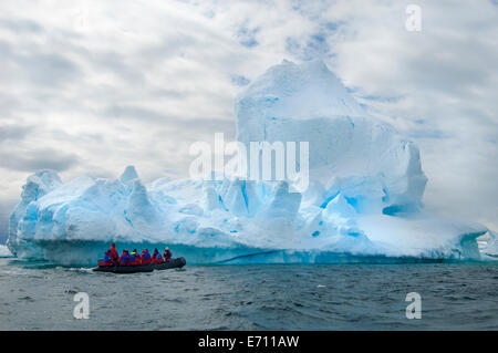 Le persone in piccoli inflatible zodiac barche di nervatura passando iceberg e ice floes intorno piccole isole dell'Antartico. Foto Stock