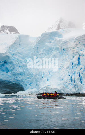Le persone in piccoli inflatible zodiac barche di nervatura passando iceberg e ice floes Foto Stock