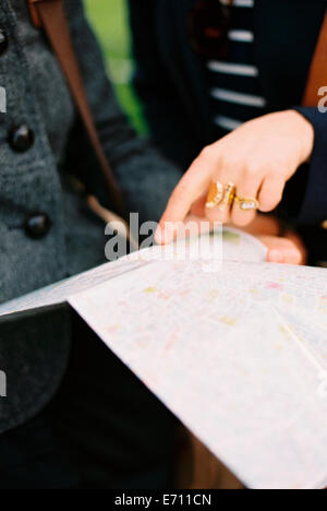 Due persone utilizzando una mappa o una guida per trovare il loro senso intorno a una città. Foto Stock