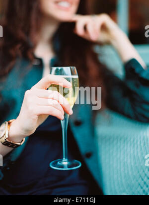 Una donna con in mano un bicchiere di vino bianco con un lungo stelo. Foto Stock