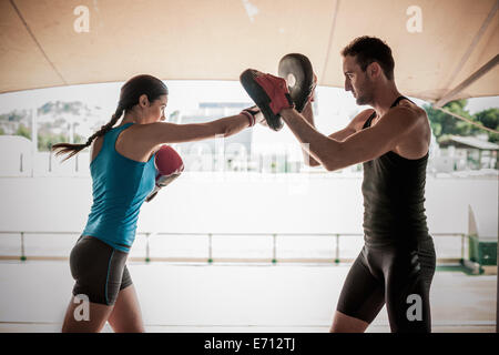 Giovane donna boxe con personal trainer Foto Stock