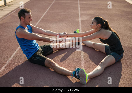 L uomo e la donna seduta sul pavimento stretching Foto Stock