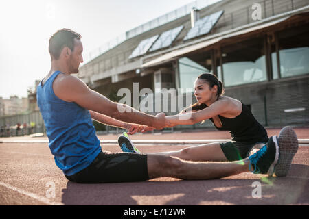 L uomo e la donna seduta sul pavimento stretching Foto Stock