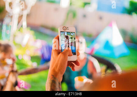 Metà uomo adulto a fotografare gli amici sullo smartphone in giardino Foto Stock