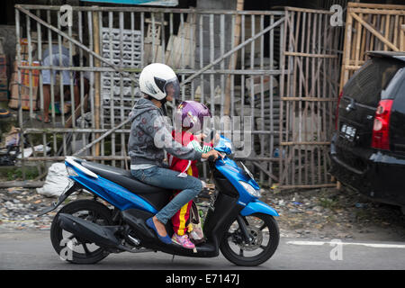 Yogyakarta, Java, Indonesia. La sicurezza stradale. La madre e la bambina sulla moto, con caschi. Foto Stock