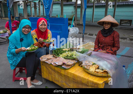 Yogyakarta, Java, Indonesia. Ragazze indonesiane a pranzo in prossimità dell' uscita dal tempio di Prambanan composto. Foto Stock