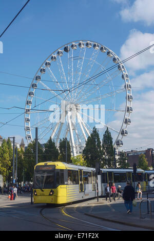 Tram Metrolink passando per Piccadilly, Manchester, con l'Occhio di Manchester in background. Foto Stock