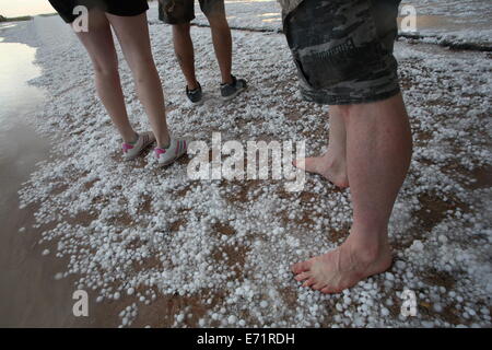 Diverse persone in piedi su una grandine di strada coperta dopo una tempesta. Foto Stock