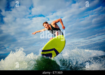 Surfista maschio in sella a bordo in estate Foto Stock