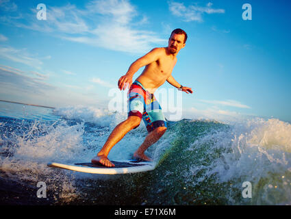 Giovane uomo surfboarding in estate Foto Stock