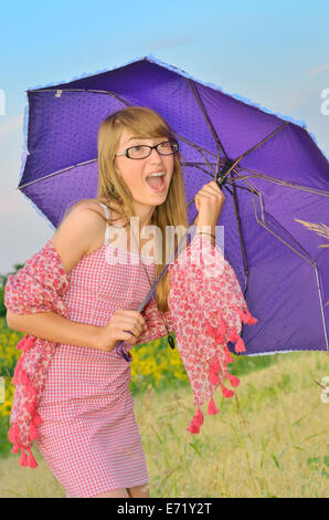 Sorpreso la ragazza con un ombrello sul campo Foto Stock