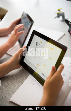 Istruzione secondaria Wales UK - una stretta di mano di due ragazze tenendo la lettura con iPad i computer tablet in un WJEC GCSE biologia classe scienze lezione in un gallese scuola secondaria Foto Stock