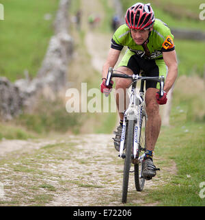 Un ciclista racing Penyghent discendente in corsia tre picchi di ciclocross. Foto Stock