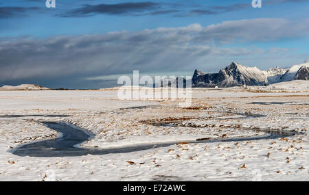 Un flusso di congelati serpeggianti attraverso la neve a Fredvang sulle Isole Lofoten Foto Stock