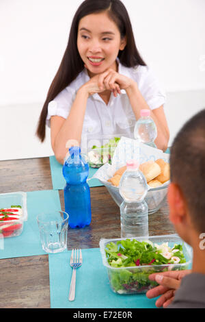 Felice giovane donna asiatica mangiare insalata con i suoi amici Foto Stock