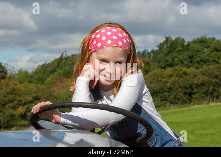 Morag Brown, età 8 anni seduto su un trattore mentre in corrispondenza di un visualizzatore di trattori d'epoca in un paese equo, Glasgow Foto Stock