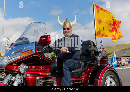 Uomo che indossa il casco Viking sul suo motorino Goldwing trike e battenti il leone rampante bandiera scozzese, durante il Viking Festival, Foto Stock