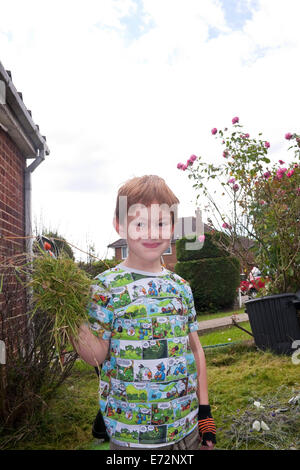 Un bambino di cinque anni, Boy aiutare fuori con il giardinaggio Foto Stock