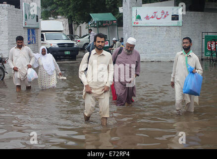 Lahore, Pakistan. 4° settembre 2014. Pakistani passano attraverso l'accumulo di acqua piovana sulle strade dopo le forti piogge monsoniche provocato inondazioni a Lahore. I funzionari di detto, " di più di 40 persone sono state uccise e decine di feriti in incidenti stradali come un risultato di forti piogge monsoniche'. Un avvertimento per più intense piogge e inondazioni è dato entro 48 ore. Credito: Rana Sajid Hussain/Pacific Press/Alamy Live News Foto Stock