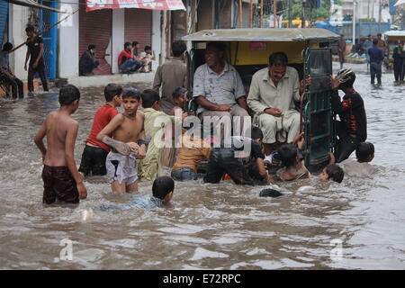 Lahore, Pakistan. 4° settembre 2014. Pakistani passano attraverso l'accumulo di acqua piovana sulle strade dopo le forti piogge monsoniche provocato inondazioni a Lahore. I funzionari di detto, " di più di 40 persone sono state uccise e decine di feriti in incidenti stradali come un risultato di forti piogge monsoniche'. Un avvertimento per più intense piogge e inondazioni è dato entro 48 ore. Credito: Rana Sajid Hussain/Pacific Press/Alamy Live News Foto Stock